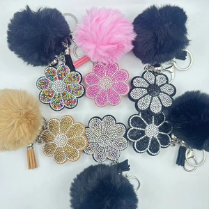 Macro detail of plush faux fur pompom keychains with sparkling rhinestone daisy flowers