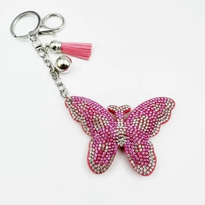 Détail du porte-clés papillon rose avec pompon en daim et strass brillants sur métal