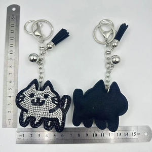 Close-up of cat keychain with white rhinestones, blue tassel and metal ruler for size scale