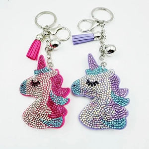 Detail showing two crystal unicorn keychains with sparkling tassels and small silver bells
