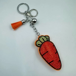Détail macro du porte-clés carotte en strass avec pompon orange et clochette en argent