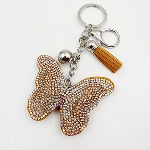Détail du porte-clés papillon en cristal avec strass irisés et pompon en daim marron