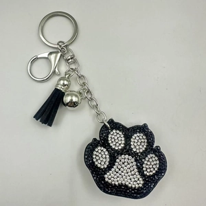 Detail van strass berenpoot sleutelhanger met zwarte kwast en zilveren belletje