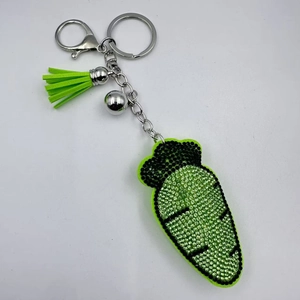 Détail du porte-clés carotte en strass avec pompon vert et petit grelot argenté chic