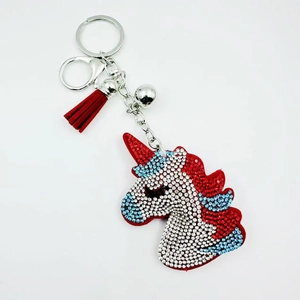 Detailed view of red and white rhinestone unicorn keychain with red leather tassel and bell