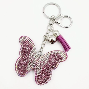 Détail d'un porte-clés papillon en strass violets avec pompon assorti et fermoir argent