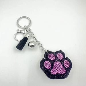 Gedetailleerd beeld van kattenpoot sleutelhanger met strass, zwarte kwast en zilveren bel
