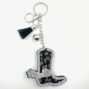 Detail of western cowboy boot keychain with black rhinestones and leather tassel
