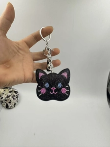 Detailed close-up of a cat head keychain featuring sparkling black and pink rhinestones