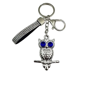 Détail du porte-clés hibou avec yeux en pierres bleues et lanière en strass noirs