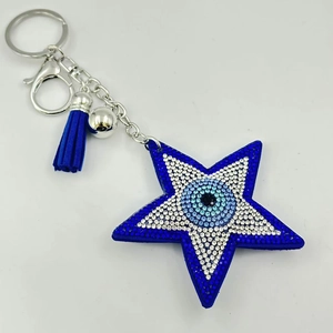 Vue détaillée du porte-clés étoile mauvais œil avec strass bleus, pompon et clochette