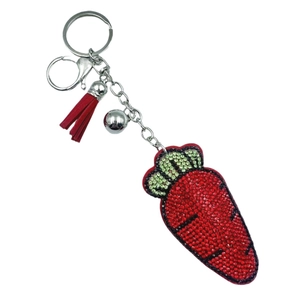 Porte-clés carotte en strass brillant avec pompon en cuir rouge et clochette sur fond blanc
