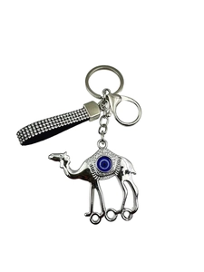 Détail d'un porte-clés chameau argenté avec œil maléfique bleu et lanière en strass