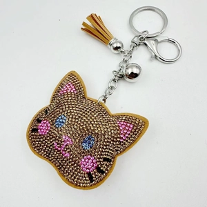 Detailed view of rhinestone cat keychain with brown leather tassel and silver bell