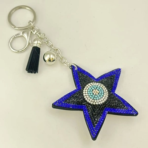 Détail du porte-clés étoile œil protecteur avec strass bleus et pompon en cuir noir