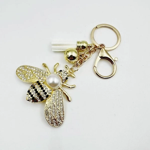 Golden bee keychain with pearl and rhinestones featuring white tassel and metal clasp