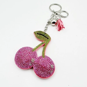 Detailed view of pink rhinestone cherry keychain with green leaves and a pink velvet tassel