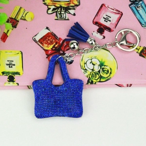 Vue détaillée d'un porte-clés sac à main bleu orné de strass avec des pompons en cuir