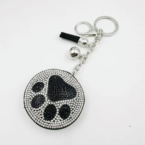 Sparkling rhinestone bear paw keychain with a black tassel and silver bell accessory