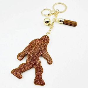 Golden Bigfoot keychain with amber rhinestones and a brown tassel charm for bags