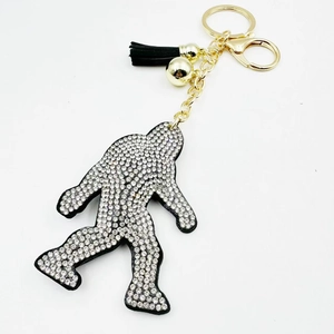 Sparkling rhinestone bigfoot keychain with gold chain and black tassel on white background