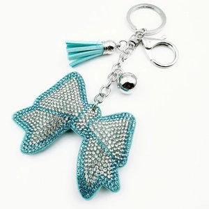 Detail of a sparkling crystal bow keychain with light blue tassels and silver bells