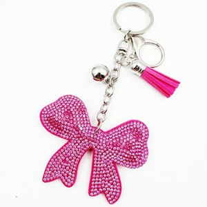 Pink rhinestone bowknot keychain with tassel and silver bell on white background