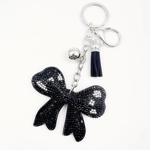 Macro shot of black velvet bow keychain with crystal flower detail and leather tassel