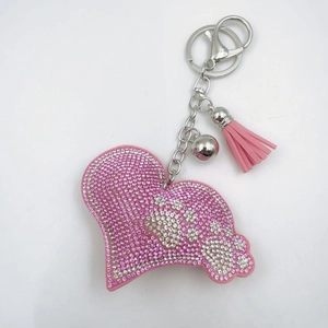 Close-up of pink rhinestone heart keychain with white paw print and soft suede tassel