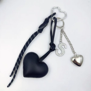 Close-up of black PU leather heart keychain with rhinestone letter S and metal heart
