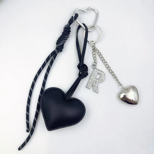 Detail of black PU leather heart keychain with rhinestone letter R and silver charms