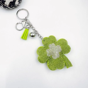 Green and white four-leaf clover keychain with sparkling crystals and a vibrant leather tassel