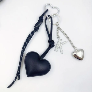 Close-up of heart-shaped PU leather keychain with rhinestone letter K charm and woven cord