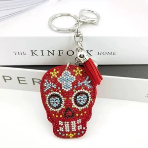 Red skull keychain with colorful rhinestones and leather tassel on white books
