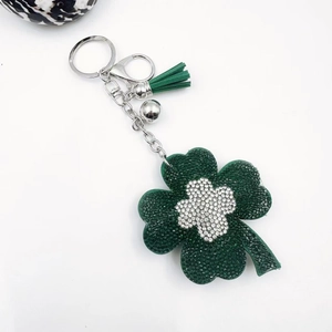 Detail of four-leaf clover keychain with green rhinestones, tassels and silver bell