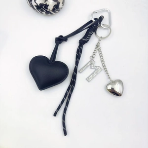 Detail of black leather heart charm with rhinestone M letter and silver snap hook