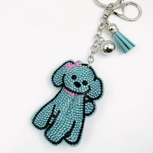 Gros plan d'un porte-clés caniche bleu clair avec strass, pompon et clochette