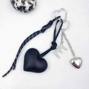 Detail of PU leather heart keychain with rhinestone letter E and woven rope accessory