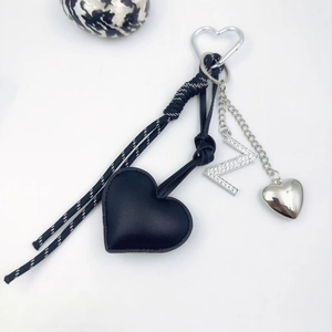 Detail of PU leather heart keychain with rhinestone letter N and braided cord on white background