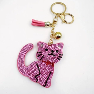 Detailed close-up of a pink rhinestone cat keychain with gold metal clasp and suede tassel