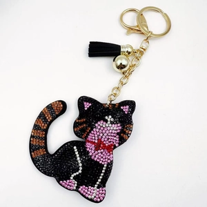 Macro detail of cat keychain with black crystals, golden lobster clasp and black tassel