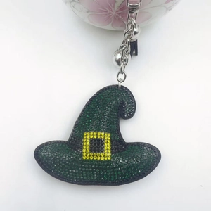 Détail d'un porte-clés chapeau de sorcière en strass verts avec boucle jaune et chaîne argent