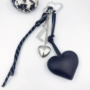 Detail of black leather heart keychain with rhinestone letter L and woven cord