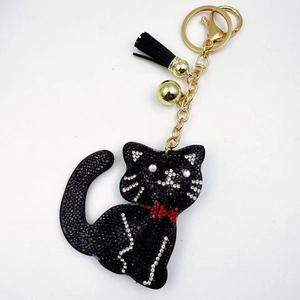 Detail of black rhinestone cat keychain with golden bell and fringe tassel pendant