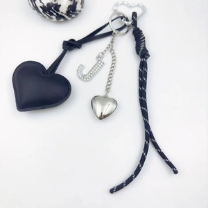 Detail view of heart charms and crystal letter J on black textured leather keychain