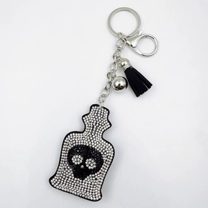 Detail view of crystal rhinestone skull keychain with black tassel and silver metal clasp