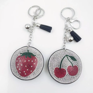 Detail of strawberry and cherry rhinestone keychains with tassels and lobster clasps