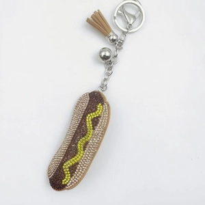 Detail of hot dog keychain with brown rhinestones, silver bell and tan leather tassel