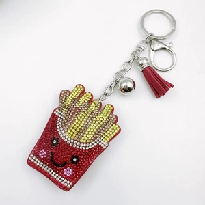 Close-up of sparkling rhinestone french fries keychain with leather tassel and silver bell