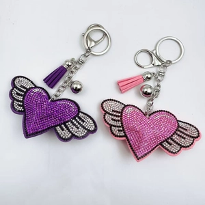 Detailed close-up of pink and purple rhinestone heart keychains with wings and tassels